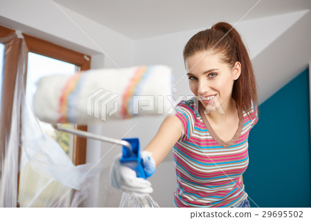 Beautiful young woman painting wall in room 29695502