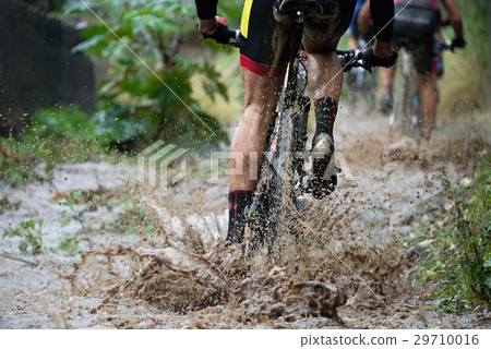 Mountain biker driving in rain upstream creek 29710016
