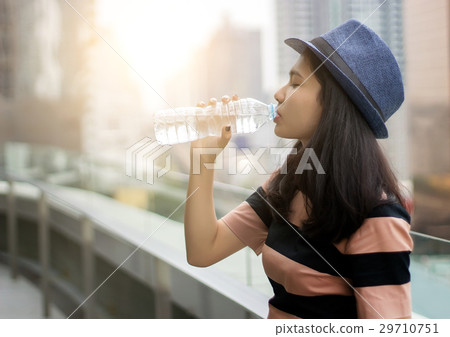 asian girl drinking water from bottle in morning light 29710751