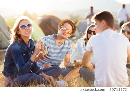 Teenagers sitting on the ground in front of tents Teenagers sitting on the ground in front of tents 29711572