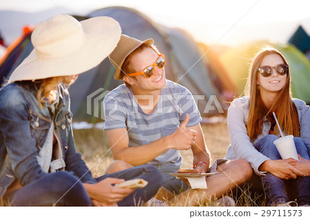 Teenagers sitting on the ground in front of tents Teenagers sitting on the ground in front of tents 29711573
