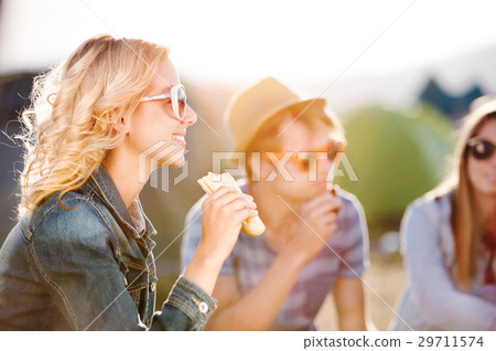 Teenagers sitting on the ground in front of tents 29711574