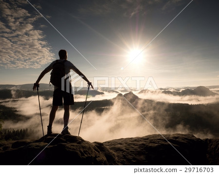 Hiker with backpack reaches the summit of mountain Hiker with backpack reaches the summit of mountain 29716703