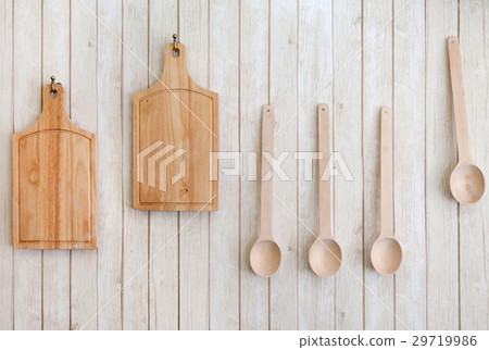 cutting boards and wooden spoons hanging on wall 29719986