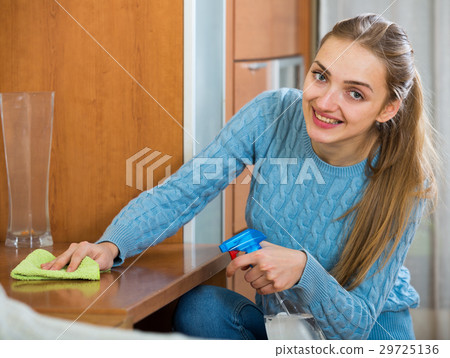 Happy housewife in sweater dusting table in living room Happy housewife in sweater dusting table in living room 29725136