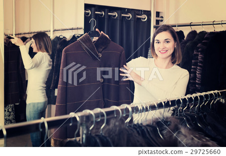 Beautiful girl customer examining sheepskin coat 29725660