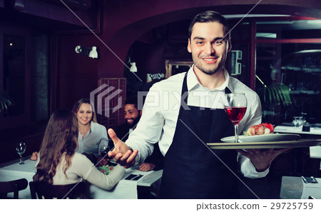 Glad young waiter taking care of adults 29725759