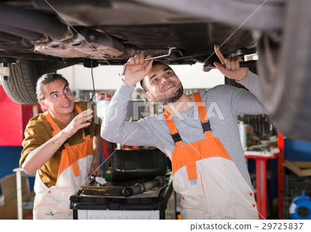 Mechanics fixing lifted up sedan 29725837