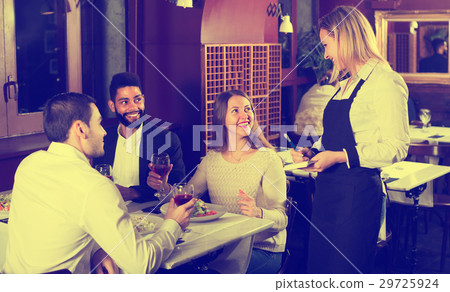 Smiling waitress and guests at the table . Smiling waitress and guests at the table . 29725924