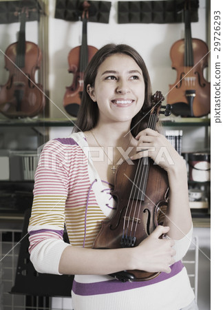 Girl choosing violin in music shop. 29726293