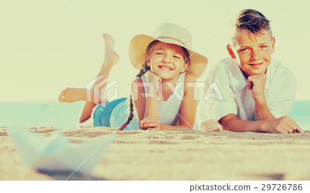 boy and girl lying on sandy beach 29726786