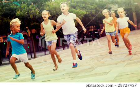 kids actively playing and running together on street on summer d 29727457