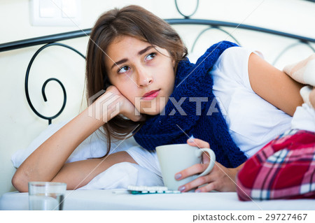 Sick teenage girl with hot tea and medication indoors Sick teenage girl with hot tea and medication indoors 29727467