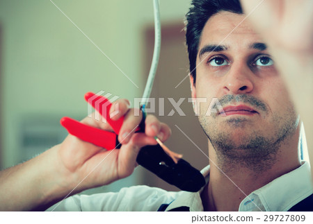 Repairman cutting wires with pliers in domestic interior Repairman cutting wires with pliers in domestic interior 29727809