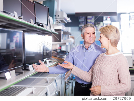 smiling husband and wife choose for themselves TV in center of electronics 29727969