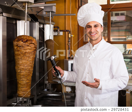 Young male chef with meat on grill 29728431