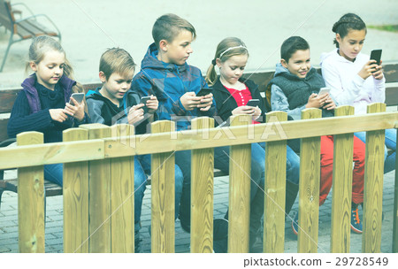 Outdoor portrait of girls and boys playing with phones Outdoor portrait of girls and boys playing with phones 29728549