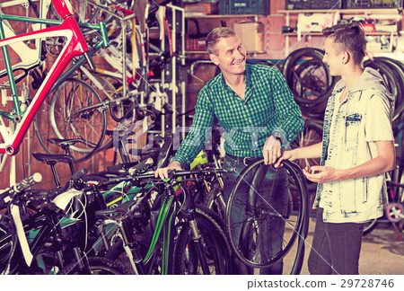 Man and teenage boy choosing new wheel 29728746