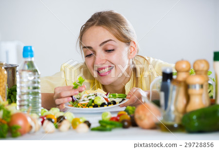Cheerful girl decorating fresh salad with herbs Cheerful girl decorating fresh salad with herbs 29728856