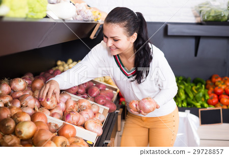 Young smiling woman choosing onions Young smiling woman choosing onions 29728857