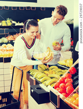 Glad adult couple deciding on fruits in shop Glad adult couple deciding on fruits in shop 29729037