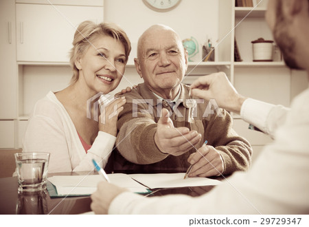 Old man and woman sign sale agreement 29729347