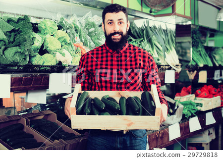 Man seller showing zucchinis in grocery shop Man seller showing zucchinis in grocery shop 29729818