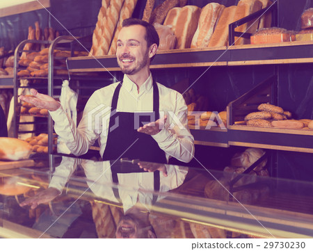 Optimistic male seller showing assortment of bakery 29730230
