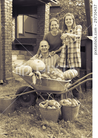 Man and two women with vegetables in garden 29730437
