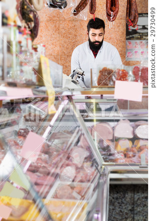 Young male seller weighing meat to sell in shop Young male seller weighing meat to sell in shop 29730499
