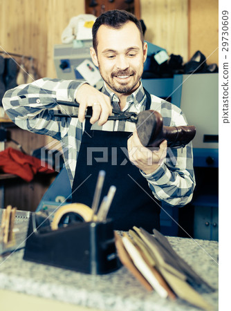 Smiling man worker working at restoring boots 29730609