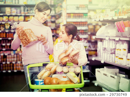 smiling woman with daughter choosing bread in supermarket 29730749