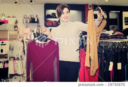 Laughing female deciding on pretty blouse 29730870