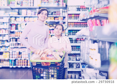 Woman with girl looking for food in supermarket 29730918