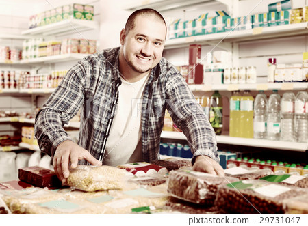Male customer choosing nuts and grain in average food shop 29731047