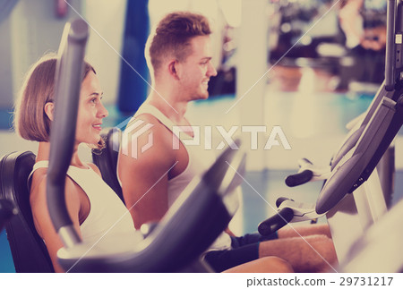 Man and woman workout using cycling cardio machines Man and woman workout using cycling cardio machines 29731217