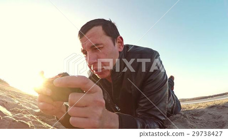 Portable console. Man lies on the sand and plays Portable console. Man lies on the sand and plays 29738427