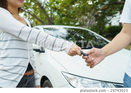 women giving a key car to young man in font of car 29743023