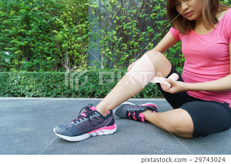 woman runner knee being applied bandage by herself 29743024