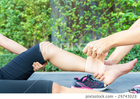 woman runner ankle being applied bandage by man 29743028