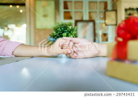 A couple holding hands each other with a gift A couple holding hands each other with a gift 29743431