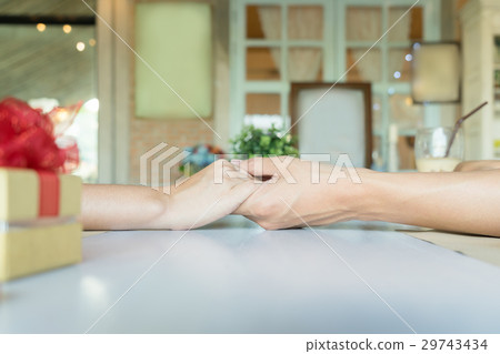 A couple holding hands each other with a gift A couple holding hands each other with a gift 29743434
