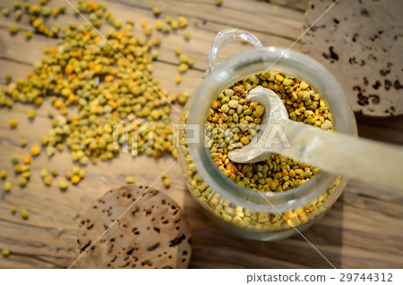 Grains of bee pollen in jar and wooden spoon on 29744312
