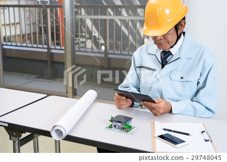 Workers overseeing the tablet at the office where the construction site is visible 29748045
