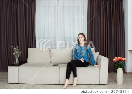 Portrait of happy young woman sitting on sofa Portrait of happy young woman sitting on sofa 29748824