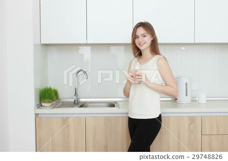 Young woman in the kitchen drinking water Young woman in the kitchen drinking water 29748826