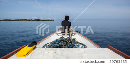 man sits on the front of a fishing boat looking at man sits on the front of a fishing boat looking at 29763385
