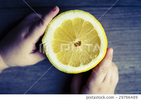 beautiful fresh yellow lemon in child hands on the wooden rustic table 29766489