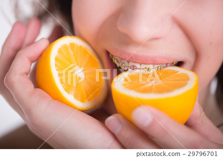 Girl with multi-colored braces tastes a lemon Girl with multi-colored braces tastes a lemon 29796701