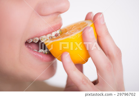 Girl with multi-colored braces tastes a lemon 29796702